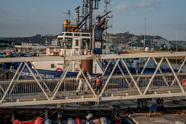 A child picked up in the English Channel aboard a boat is brought ashore by Border Force at Dover. Below lie abandoned dinghies used by asylum seekers to cross the channel.