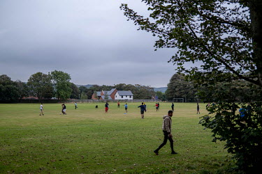 Asylum seekers play football on a field next to Napier Barracks. The delapidated former Army barracks are being used to house refugees who have been picked up on the English Channel.