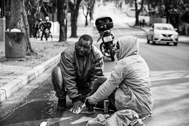 Ugandan delivery driver Bashir puts ice on a colleague's injured foot after he crashed with his bike.