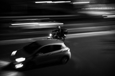 A food delivery rider in traffic at night in Johannesburg.