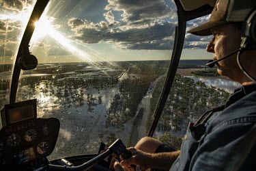 Helicopter pilot Bryce Guest flying his craft, helping to move farmers between their properties and town and dropping off supplies to farmers cut off by flood waters.