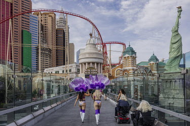 Women wearing costumes and charging to take pictures with tourists walk along a catwalk in Las Vegas.