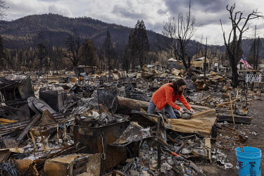 Tami Spang, 57, a former gold miner, searches for objects in the rubble of her home, a trailer, which was destroyed by a wildfire in the historic Northern California town of Greenville. The town was d...