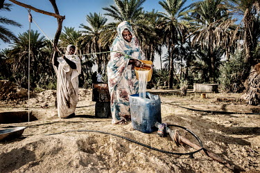 Women get water from a well for irrigation. They work for a cooperative which manages a plantation in the oasis.