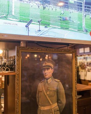 A military portrait of Mustafa KemalAtaturk hangs below a television broadcasting a football match in one of Kadikoy's manybars.
