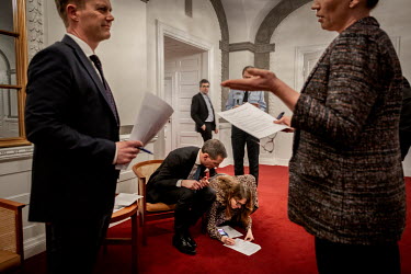 Danish Prime Mette Frederiksen talks with the Minister for Foreign Affairs, while Head of Department Barbara Bertelsen sits on the floor and corrects the Minister of Justice's papers in a frantic rush...