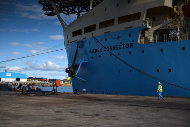 A ship worker walks to the front of a Maersk vessel which will take reels of cable out to offshore energy projects, from Bates Terminal, located on the site of the former Bates coal mine, at the Port...