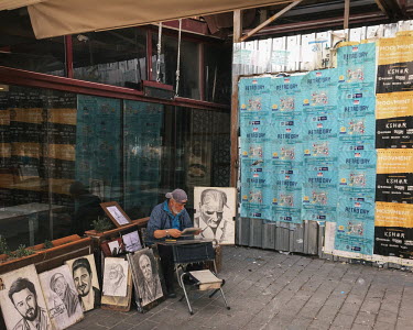 An artist working in Karakoy with a drawing of Mustafa Kemal Ataturk next to him.