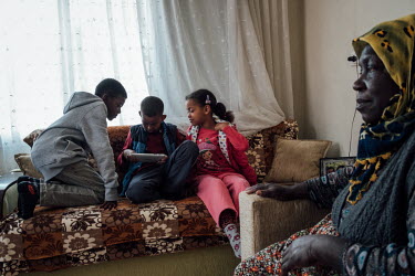 Sabriye SÄ�naic (far right) sits with her grandchildren at home in Haskoy. The children play games on an iPad after returning from school. Umut Can (left), Berke Han (holdiÄ�ng iPad) and Beyaz Nur (...