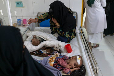 A mother holds a tube supplying medicine to her malnourished child in a therapeutic feeding unit at the Medecins Sans Frontieres (MSF) Lashkar Gah hospital, where each bed is occupied by two children.