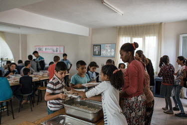Gulsen Erguven (35, wearing red, centre) working in the canteen at her village school in Yeniciftlik. Gulsen has two children at the school (the eldest to her left) and works there part time, whilst h...