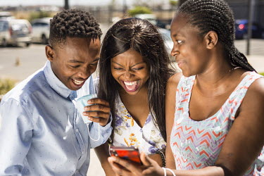 Young people laugh at something on their phones at Isivavana youth cultural center in Khayelitsha township in Cape Town.