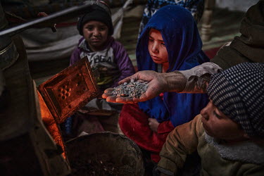 Noor Bacha (53), alongside his children and grandchildren, adds a handful of plastic to the stove in their home. The family fled their home in Nangarhar province three years previously because of figh...