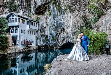 A bride and groom pose by the bandaj cave at Blagaj house. This traditional Dervish monastery with Turkish influenced architecture is the only one in Bosnia Herzegovina and is a national monument.