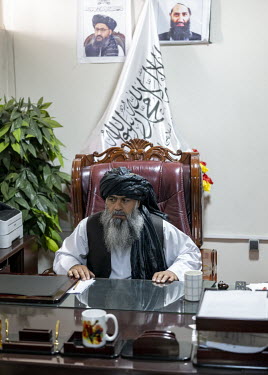 Bashir Ahmad Rustamzai, the new head of sports in the Taliban government in his office. On the wall behind him are portraits of Mollah Baradar (left) and Mollah Haibatullah Arundzada.