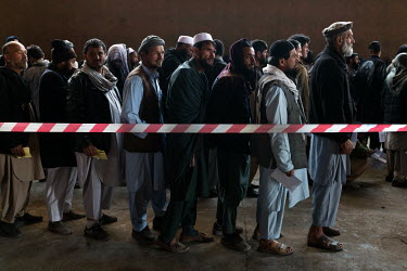 People queue for a distribution of cash by the World Food Program to the poorest people at a former gymnasium.
