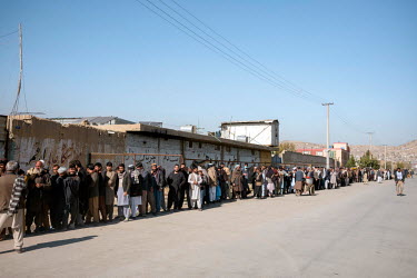People queue for a distribution of cash by the World Food Program to the poorest people at a former gymnasium.