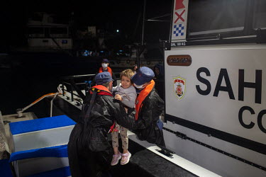 An Afghan child is lifted from the deck of a Turkish coastguard vessel whose crew had been involved in the rescue of around 20 migrants from two life rafts drifting at night in the northern Aegean Sea...