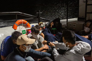 Afghan migrants huddle together on the deck of a Turkish coastguard vessel after they were rescued from two life rafts drifting at night in the northern Aegean Sea. All those on board claim to have be...