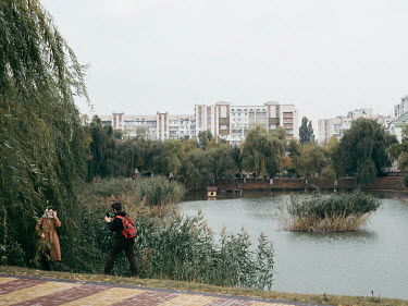 A couple take photographs in a park with a lake in city center of Tiraspol.