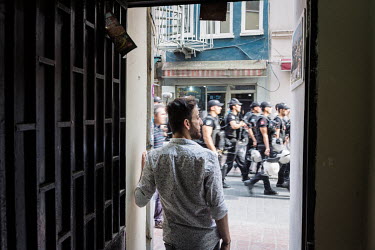 Hussein stands in the doorway of a gay friendly cafe near Mis Sokak, as riot police pass by to prevent the LGBTI Pride march from taking place.