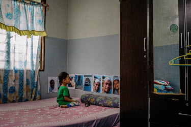 The youngest son of Hani Bin Sha'ari looks at photos of his father at the family home in Sungai Rambai. Hani Bin Sha'ari passed away after contracting COVID 19 and leaves a wife, Nancy and 4 children....