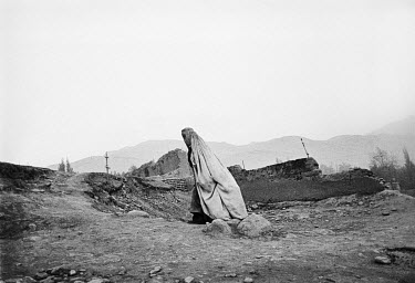 A burqa clad woman walks on a war-torn street in Faizabad.