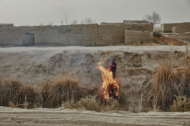 A boy burns off reeds from an irrigation canal.
