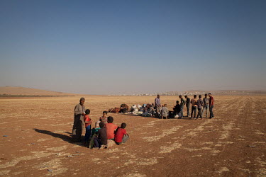 Groups of newly arrived Syrian refugees wait to be collected and taken to temporary shelters around the town of Suruc after crossing the border into Turkey. Their hometown of Kobani in Syria is behind...