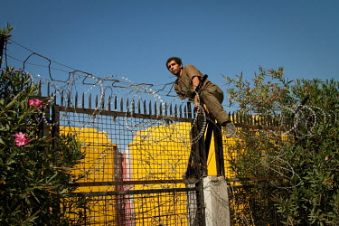 An Algerian man scales the fence surrounding the international port in Patras. From here ferries travel frequently to Italy and further afield, and where many undocumented migrants attempt to smuggle...