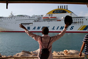 A migrant from Yemen waves to a passenger ship en route to Italy, and shouts "No room for one more?!".