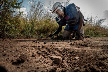 Mines Advisory Service (MAG) demining supervisor Rambo carefully investigates spots where a metal detector signalled a metal object and reveals an antipersonnel landmine.