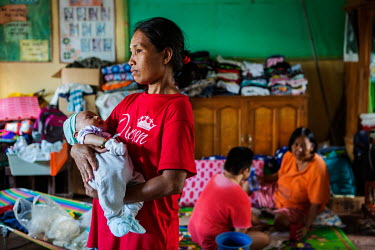 Melanie Primor (31) holds her nephew Christian Jay Jocoy (1 month) in the classroom that her family shares with four other families in the Camaya-an High School. Primor's district (purok) was ordered...