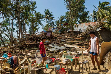 Melenio Cuajao (21) (Red Shirt) and Sherwin Dalis (18) (white shirt) help tidy up around the houses of Rolando Lismis and Marcelo Tumanda after typhoon Rai December.