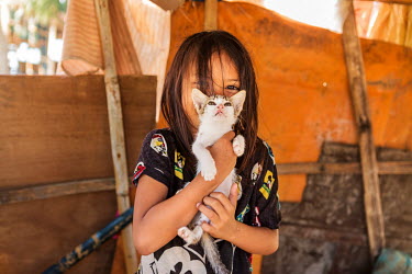 A young girl holds up a kitten in her makeshift shelter in Barangay Tapon in the aftermath of typhoon Rai.  The impact in this area was immense. Almost all of the houses in this district (purok) were...