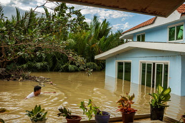 Garry Belacho (46) makes his way towards his house, through shoulder deep flood water, in the aftermath of typhoon Rai.