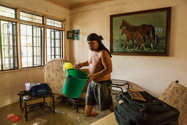 Roberto A. Laurel tries to tidy up the family home the day after typhoon Rai.