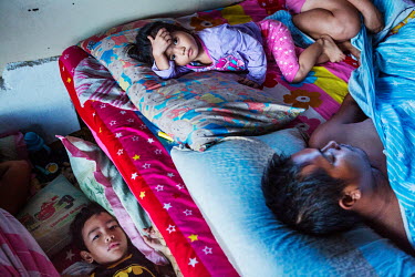 (top) Ysabella Coyno (3) on the bed with her dad Mark Gregory Coyno (30) and cousin Jess Xander Acojedo (4) on a mattress on the floor, they are some of the 45 families relocated to a mall under const...