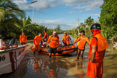 Coast Guard rescue workers prepare to load their fast boats onto a truck on a flooded road in the aftermath of typhoon Rai.