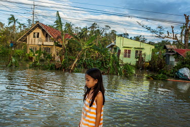Precious Taldo (8) stands in the street near her family's house in barangay Agape in the aftermath of typhoon Rai.