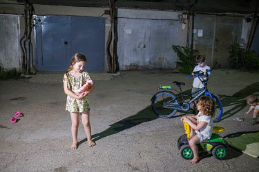 Children playing outside while their parents are partying inside a garage.