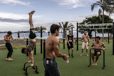 People exercise in an outdoor gym on a coastal promenade in an affluent neighbourhood.