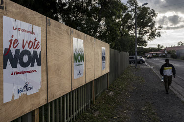 People walk past a political poster calling for people to vote 'No' to independence in the upcoming referendum, held on 12 December 2021.