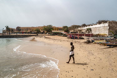 A man walks on a beach on the historic Goree Island, infamous for its prison, the departure point for enslaved Africans being transported across the Atlanic Ocean to the plantations of the Americas.