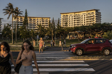 People cross a beach road in a wealthy neighbourhood popular with 'Metros', newly migrated metropolitan French citizens, and tourists.