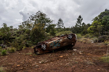A burned out, abandoned car, which was used to form a blockade of a road during the 'nickel mine conflict' in 2020, now discarded by the side of the road.