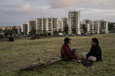 Residents of the Magenta high rise housing project sit in a park in front of the estate.