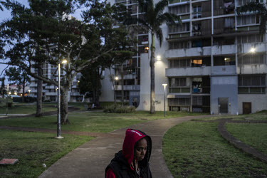 A young adult smokes marijuana outside at the Magenta housing estate. The high rise residential towers have a subsided rent but are also dilapidated.