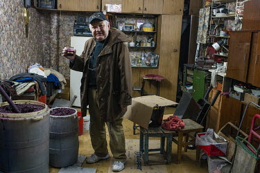 A man tastes his wine which is the process of fermentation in his garage.