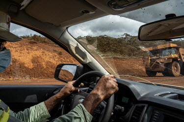 A truck loaded with nickel ore driving through the mine site, seen from a pickup truck driven by a mine supervisor at the Prony Resources Nickel Mine.